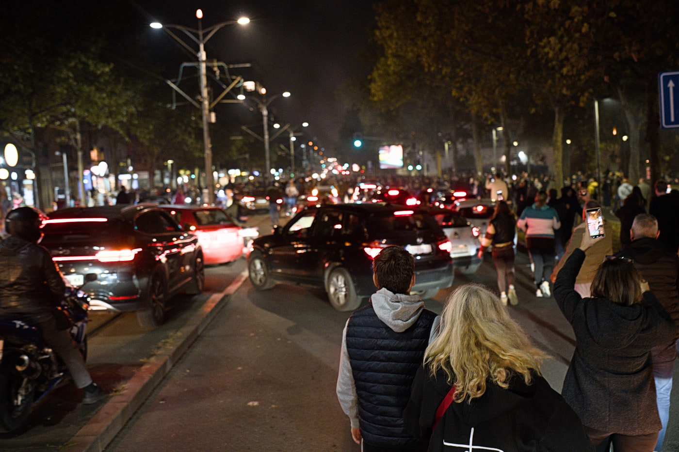 People streaming toward the National Assembly between cars stopped on Bulevar kralja Aleksandra near Vukov spomenik, the boulevard turned into a parking lot on election night