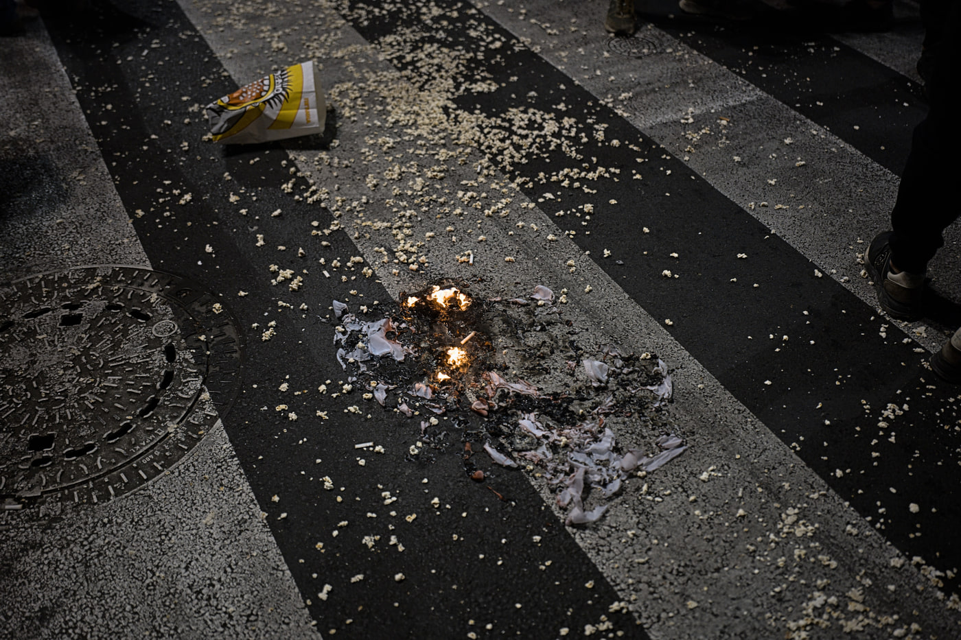 A popcorn bag burning on a zebra crossing, popcorn scattered across the street — SNS going up in smoke