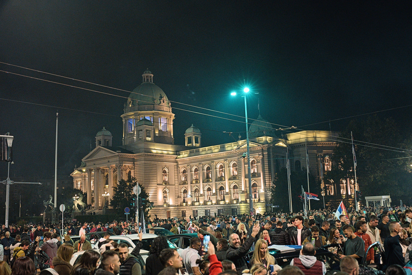 The National Assembly of Serbia, lit up and surrounded by a sea of people
